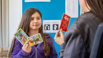 Meisje toont kaartjes tijdens een taal- of spraakoefening in de klas.