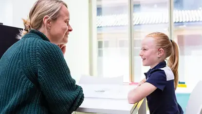 Een therapeut praat met een kind dat een hoortoestel draagt.