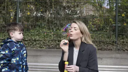 Een logopedist blaast bellen terwijl een jongen toekijkt, buiten.