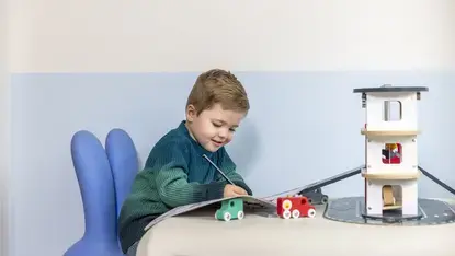 Een peuter schrijft in een boekje. 