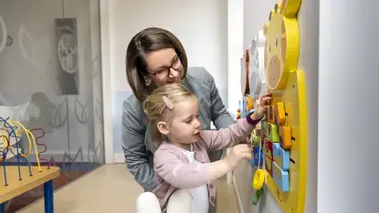 Een vrouw helpt een peuter met een kleurrijk wandspeelgoed met een giraffe.Een vrouw helpt een peuter met een kleurrijk wandspeelgoed met een giraffe.