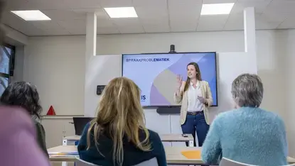 Een vrouw geeft een presentatie over spraakproblematiek voor een groep collega's.