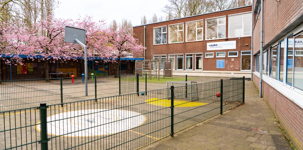 Schoolplein met op de achtergrond school inclusief locatiebord