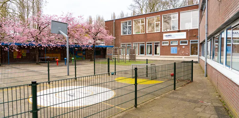 Schoolplein met op de achtergrond school inclusief locatiebord