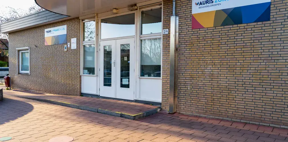Grote witte deur in een stenengebouw met bord op de gevel