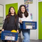 Twee leerlingen dragen lunchkratjes voor hun groep.