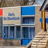 Buitenkant van het schoolgebouw van Auris De Weerklank met speeltoestel op de voorgrond.