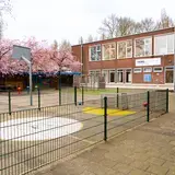 Schoolplein met op de achtergrond school inclusief locatiebord