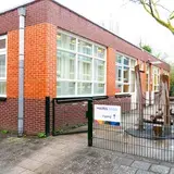 Een hek met een gebouw en een bordje met Auris Zorg
