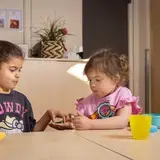 Twee leerlingen met hoortoestellen delen iets aan tafel.