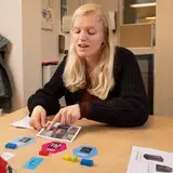 Een leerkracht legt woordkaarten en blokjes uit aan een leerling.