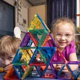 Twee kinderen liggen op de grond achter een piramide van gekleurde magnetische bouwstenen.