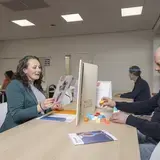 Een vrouw en een man spelen met bouwstenen aan een tafel met een bordje 'Auris Cursuscentrum'.
