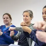 rie vrouwen maken samen een vuistgroet tijdens een oefening.
