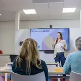 Een vrouw geeft een presentatie over spraakproblematiek voor een groep collega's.