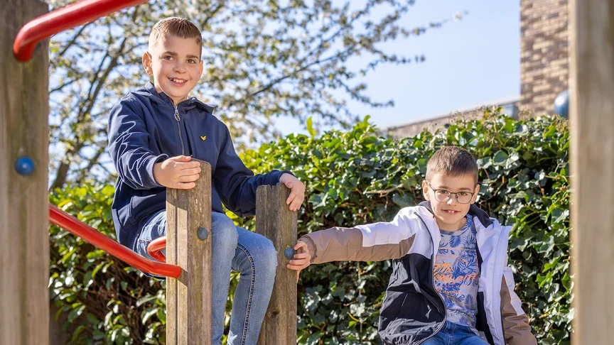 Twee lachende jongens spelen op het klimtoestel op het schoolplein.