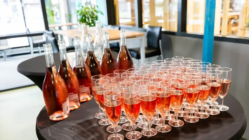 Glazen met roze drank en flessen staan klaar op een tafel.
