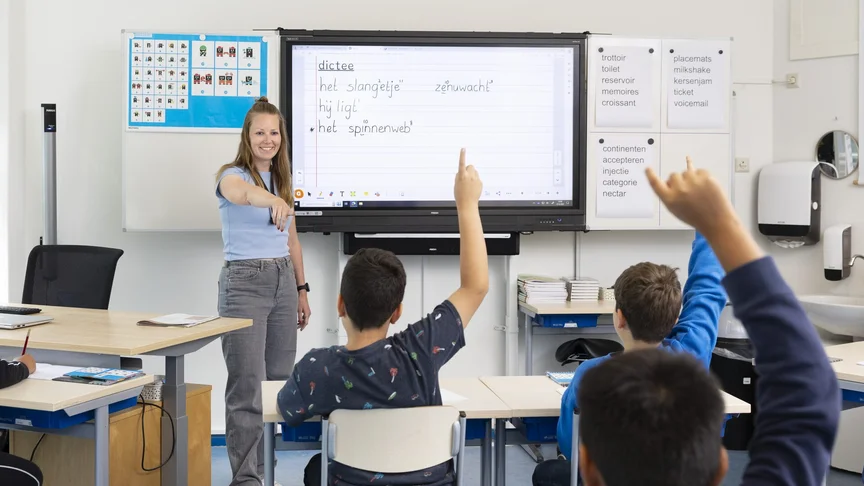 Leerkracht bespreekt een dictee met de klas, leerlingen steken hun vinger op