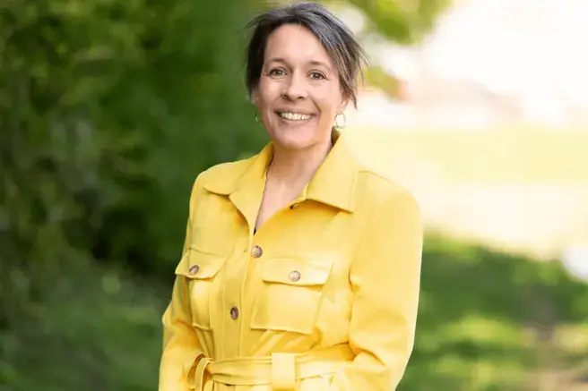 Vrouw met gele jurk aan kijkt in camera