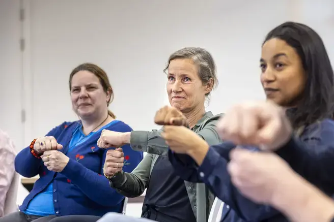 rie vrouwen maken samen een vuistgroet tijdens een oefening.